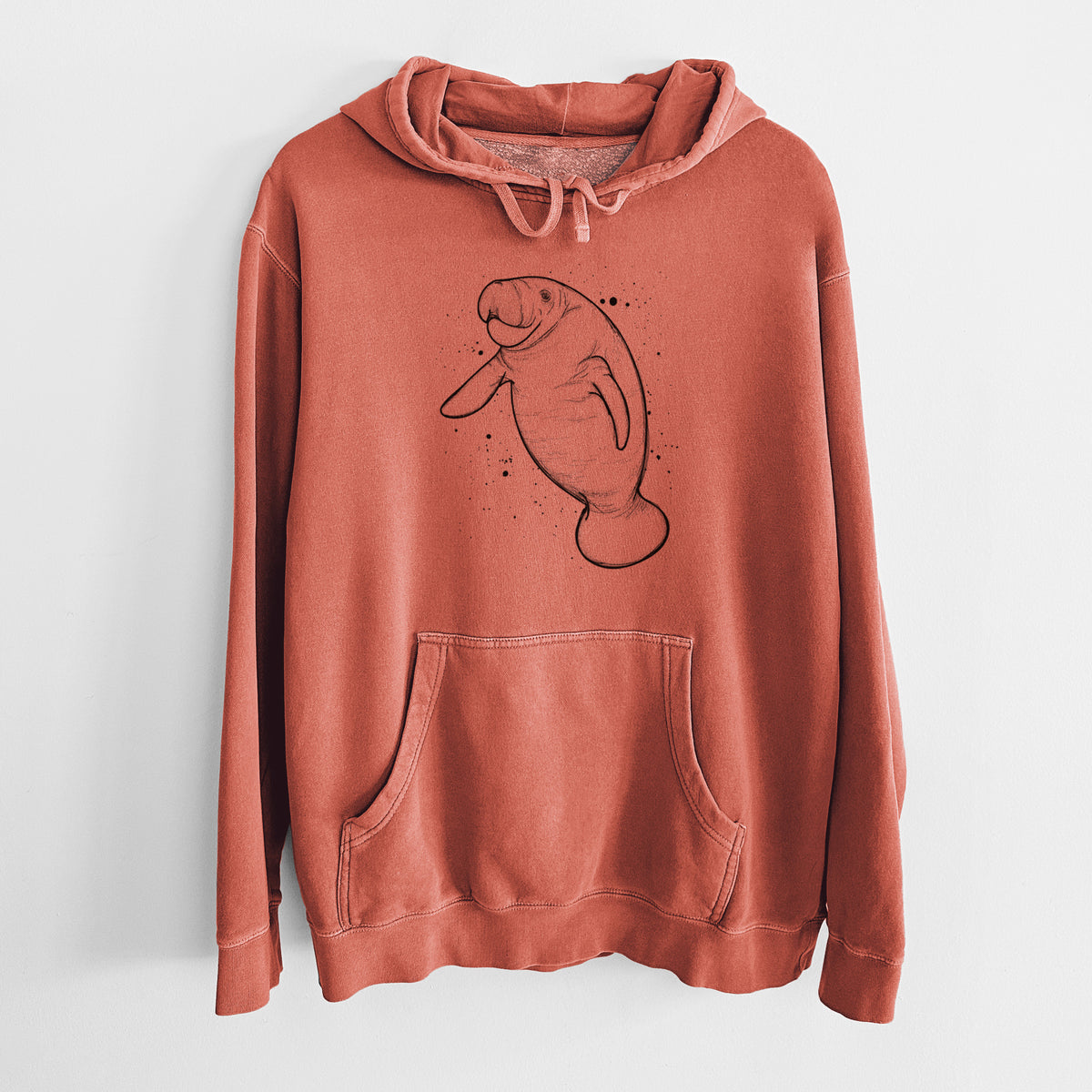Amber orange pigment dyed hoodie laid flat, printed with a black ink line drawing of a manatee swimming, with ink splatters.