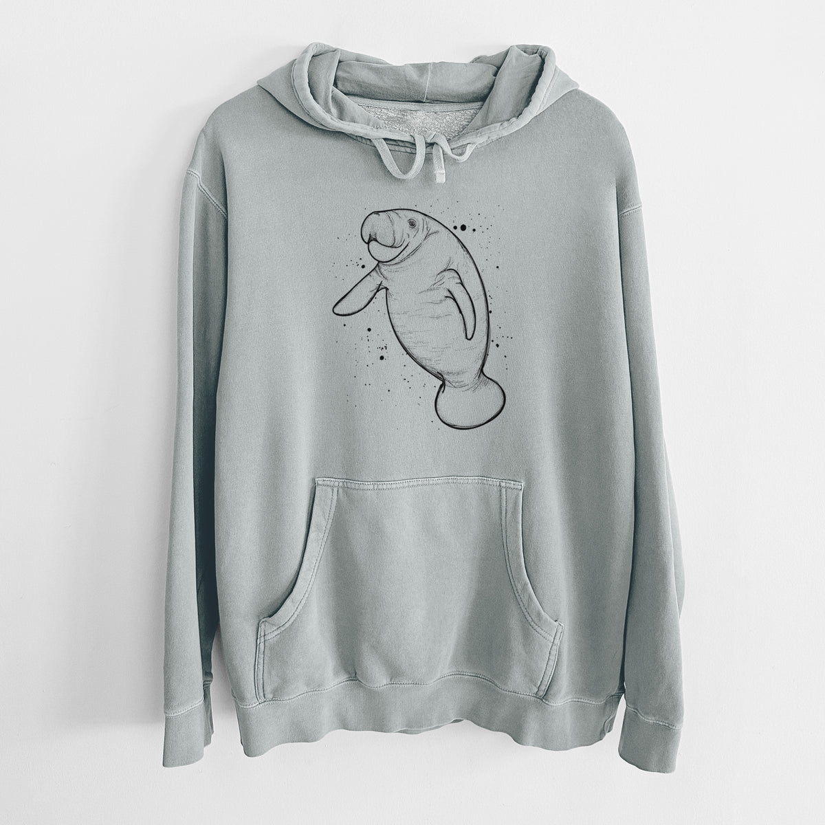 Sage green pigment dyed hoodie laid flat, printed with a black ink line drawing of a manatee swimming, with ink splatters.