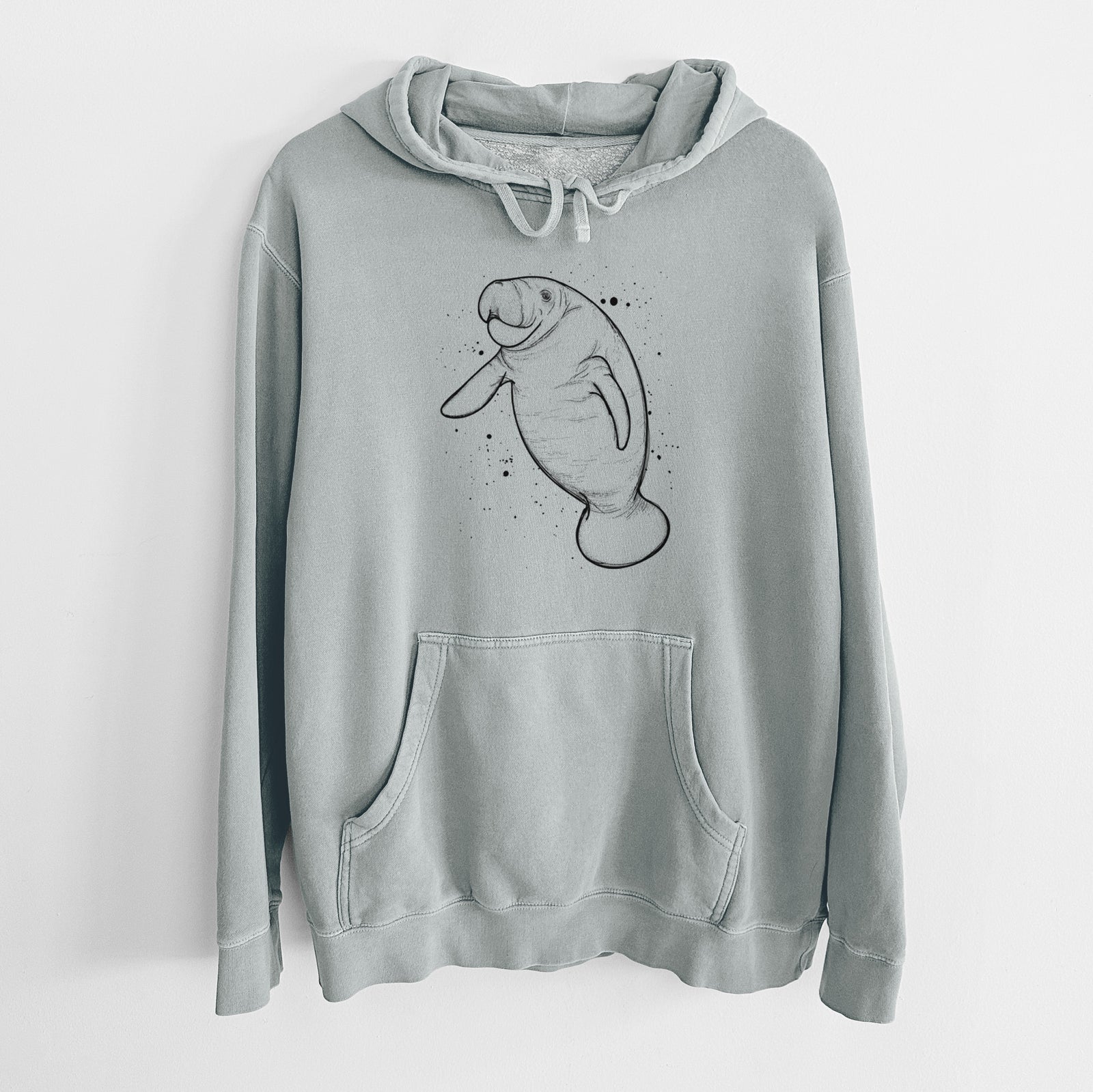 Sage green pigment dyed hoodie laid flat, printed with a black ink line drawing of a manatee swimming, with ink splatters.
