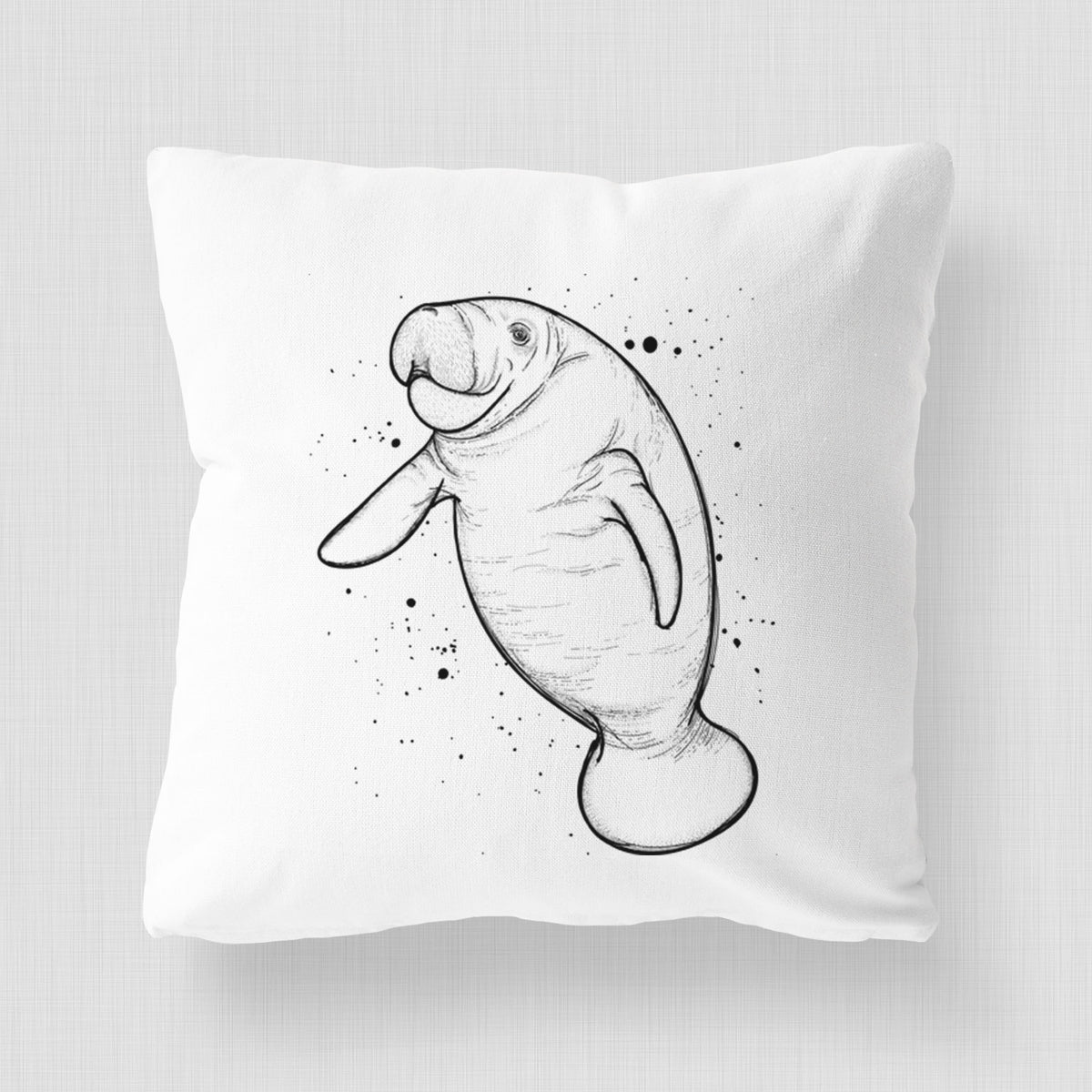 White pillow cover printed with a black ink line drawing of a manatee swimming, with ink splatters.