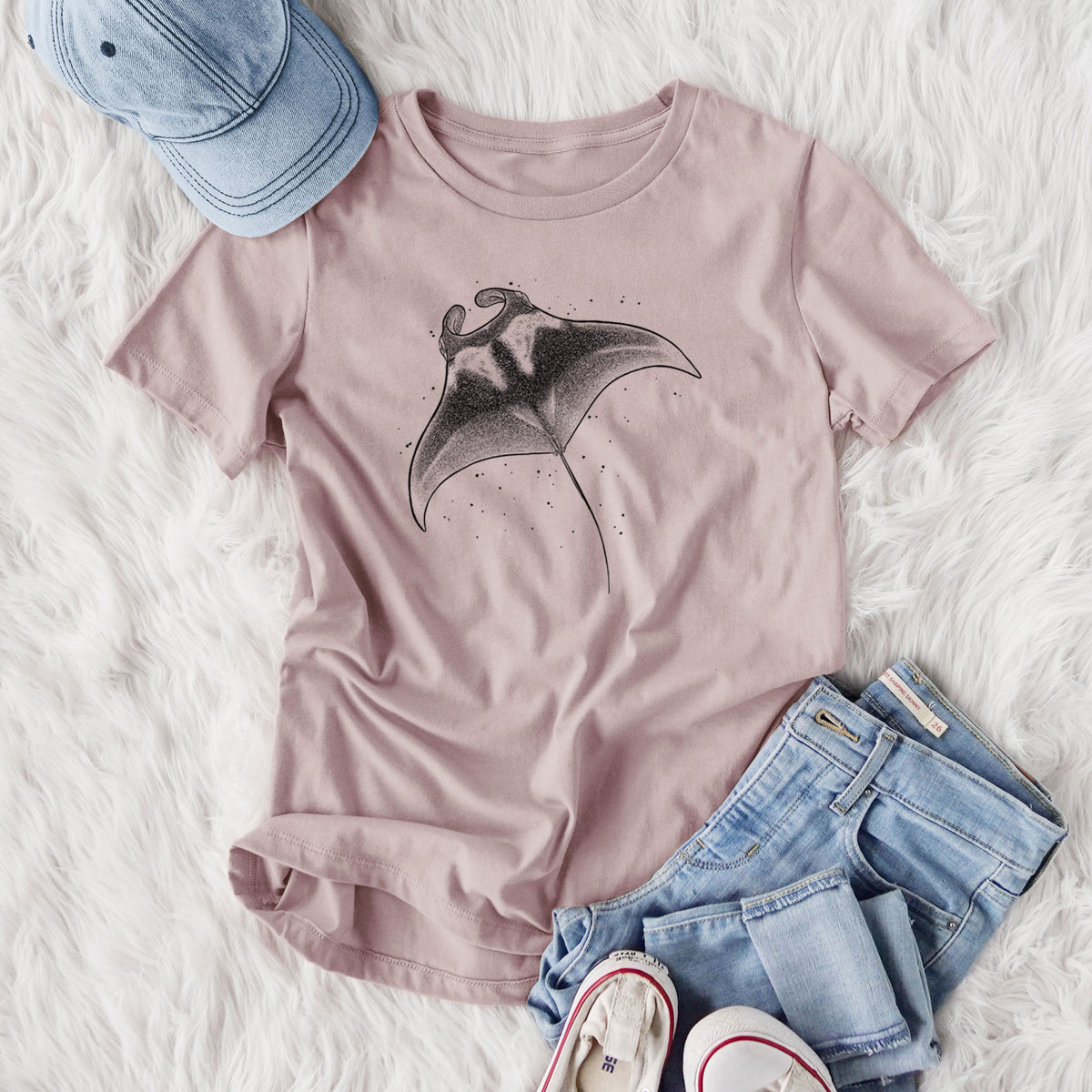 Women's relaxed fit cotton t-shirt printed with a black ink illustration of a manta ray gliding, styled flat on a white faux fur rug with jeans.