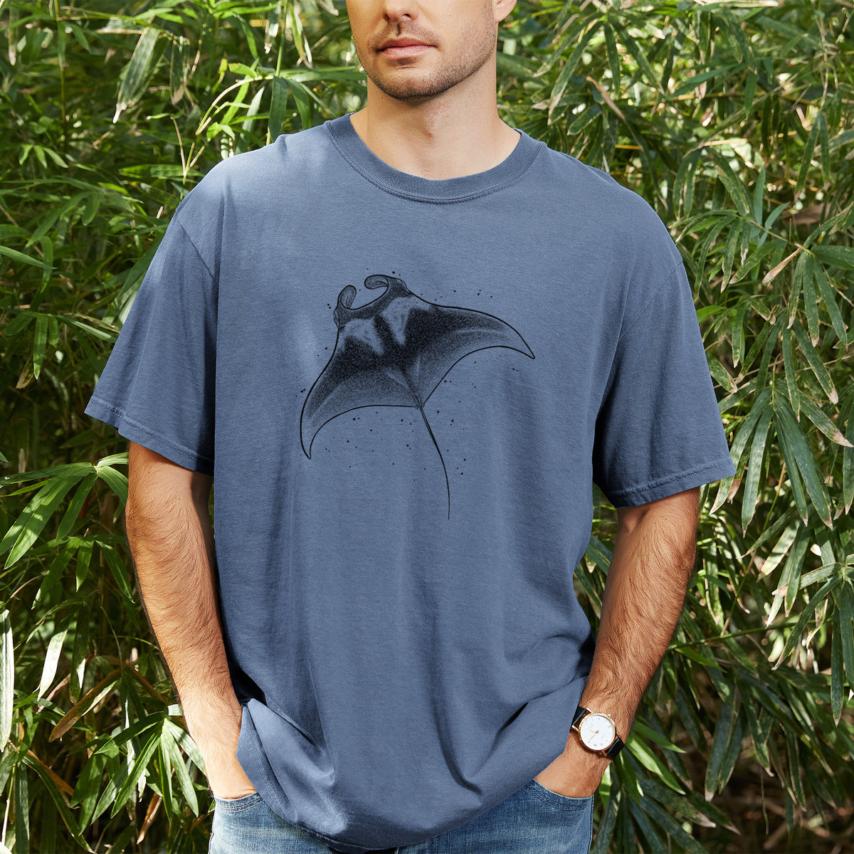 Man wearing a Comfort Colors t-shirt printed with a black ink illustration of a manta ray gliding, outdoors.
