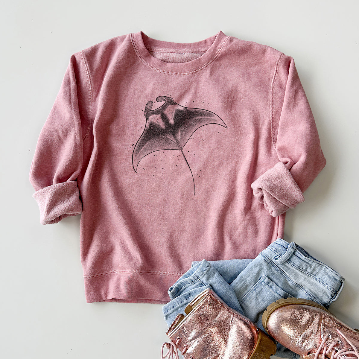Youth crewneck sweatshirt printed with a black ink illustration of a manta ray gliding, styled flat with jeans and boots.
