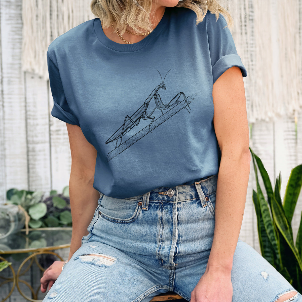Woman wearing a steel blue lightweight cotton t-shirt printed with a detailed black ink illustration of a praying mantis on a stem.