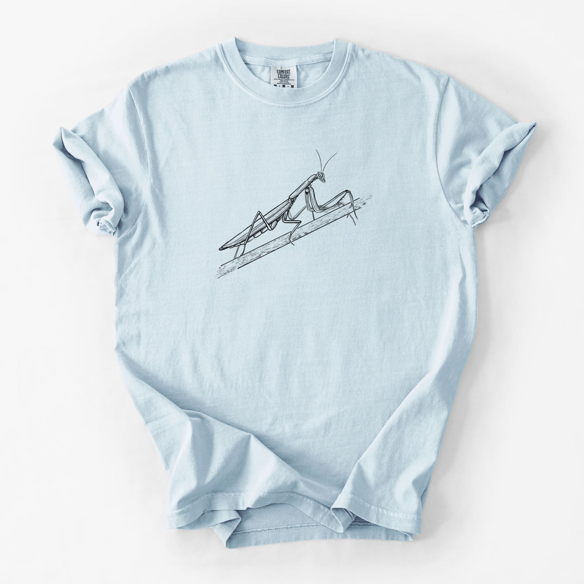 Chambray blue Comfort Colors t-shirt laid flat, printed with a detailed black ink illustration of a praying mantis on a stem.