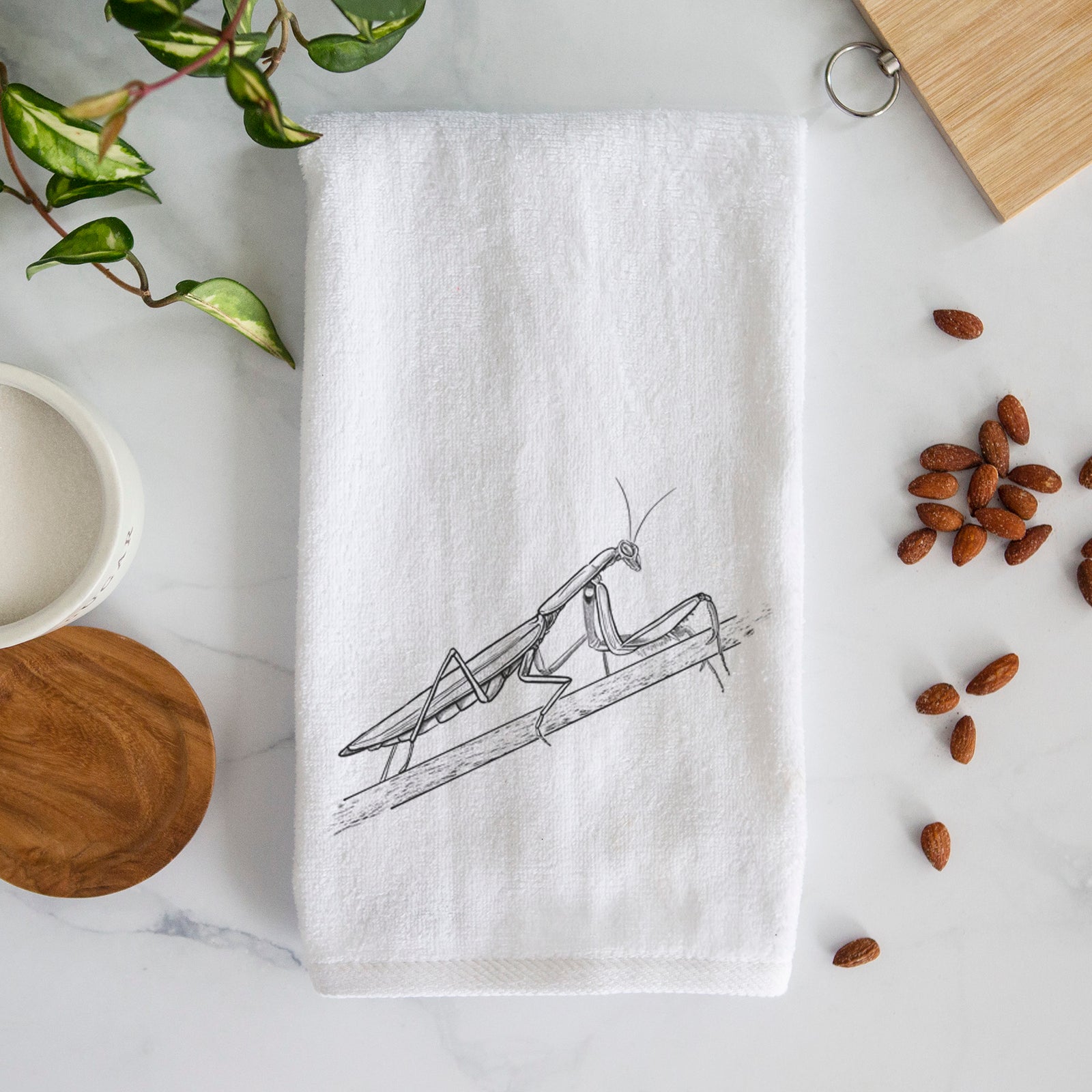 White hand towel printed with a detailed black ink illustration of a praying mantis on a stem.