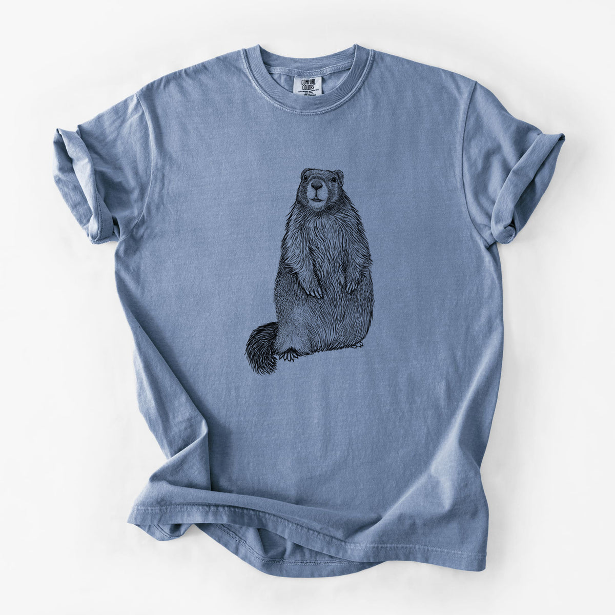 Blue jean Comfort Colors t-shirt laid flat, printed with a detailed black ink illustration of a marmot standing upright.