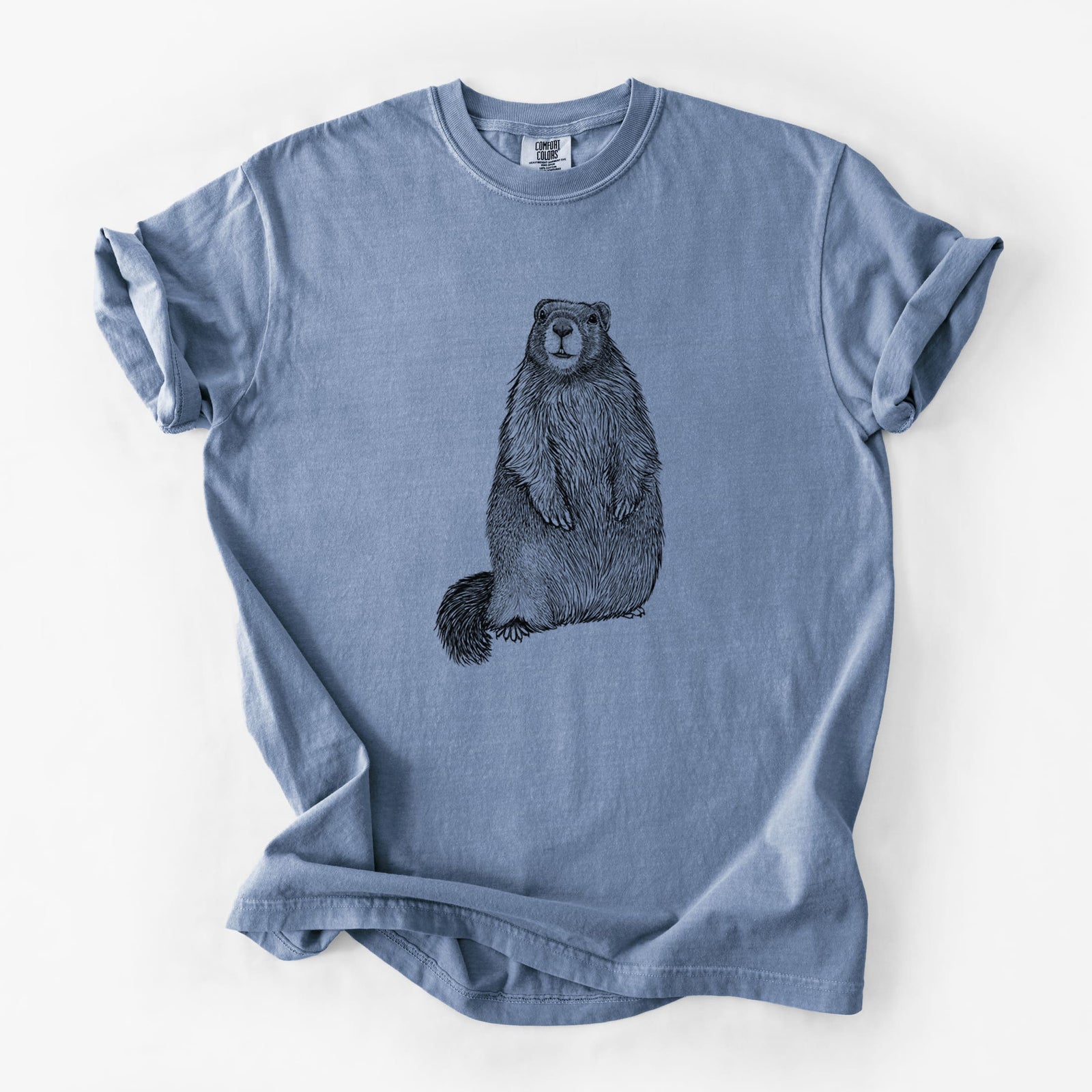 Blue jean Comfort Colors t-shirt laid flat, printed with a detailed black ink illustration of a marmot standing upright.