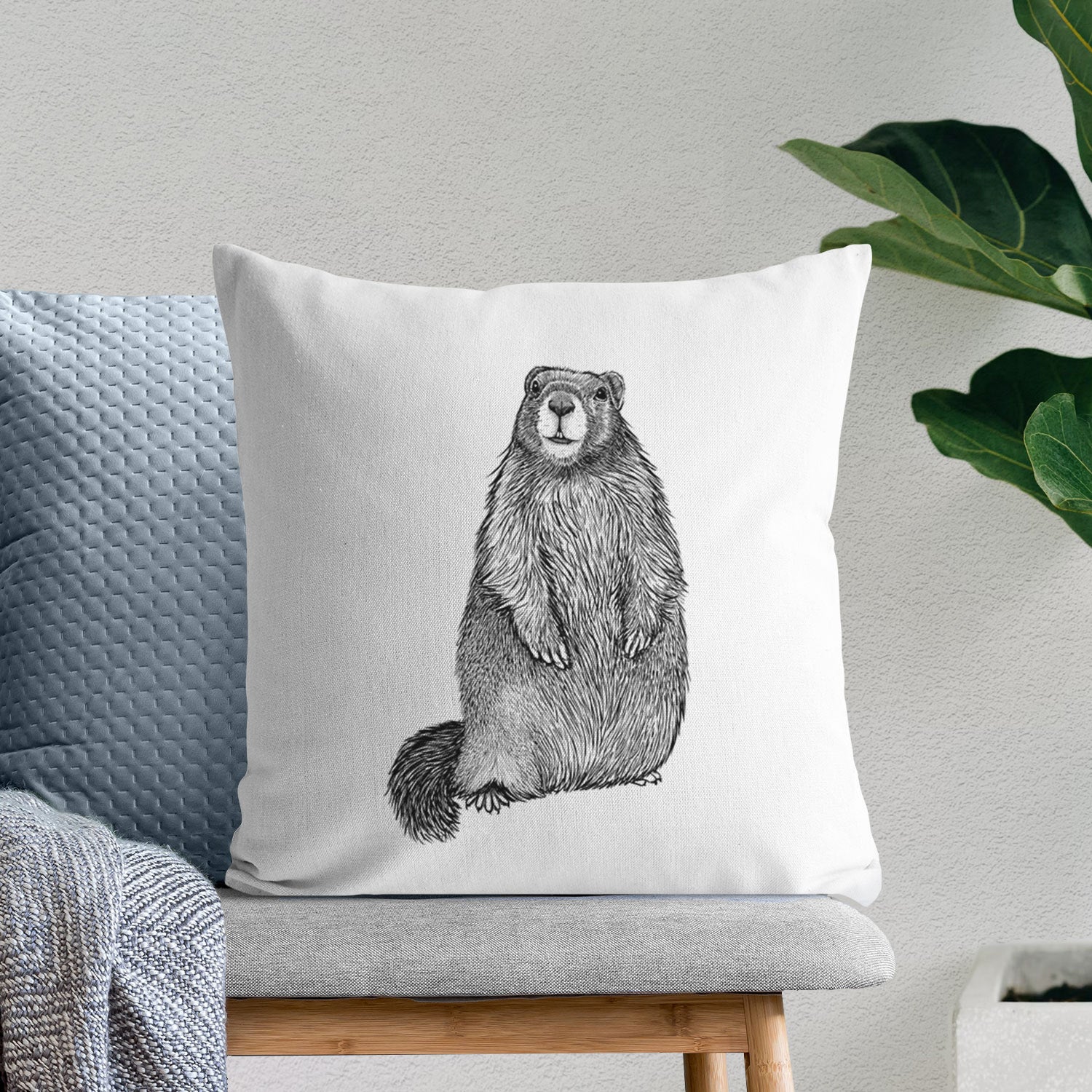 White pillow cover printed with a detailed black ink illustration of a marmot standing upright, on a bench beside plants.