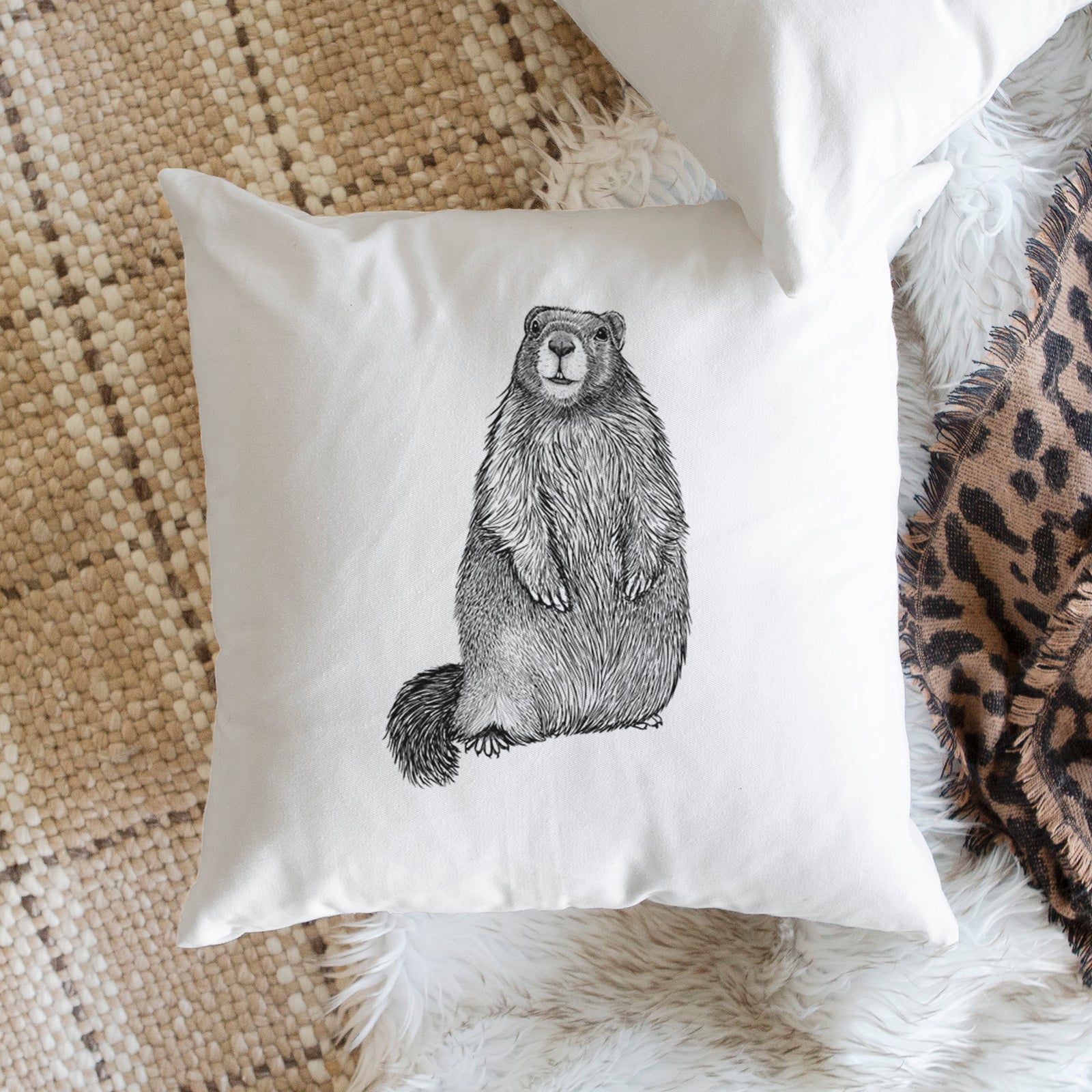 White pillow cover printed with a detailed black ink illustration of a marmot standing upright, on a bench beside plants.