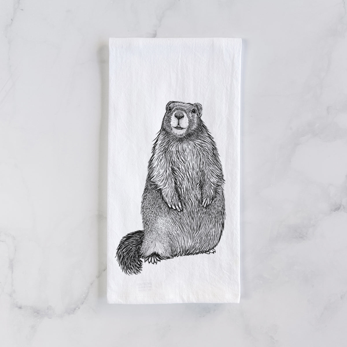 White cotton tea towel laid flat on marble, printed with a detailed black ink illustration of a marmot standing upright.