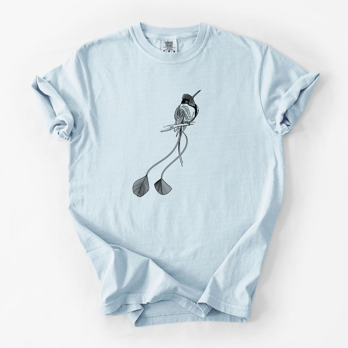 Chambray blue Comfort Colors t-shirt laid flat, printed with a black ink illustration of a marvelous spatuletail hummingbird perched, with its two long racket-tipped tail feathers.