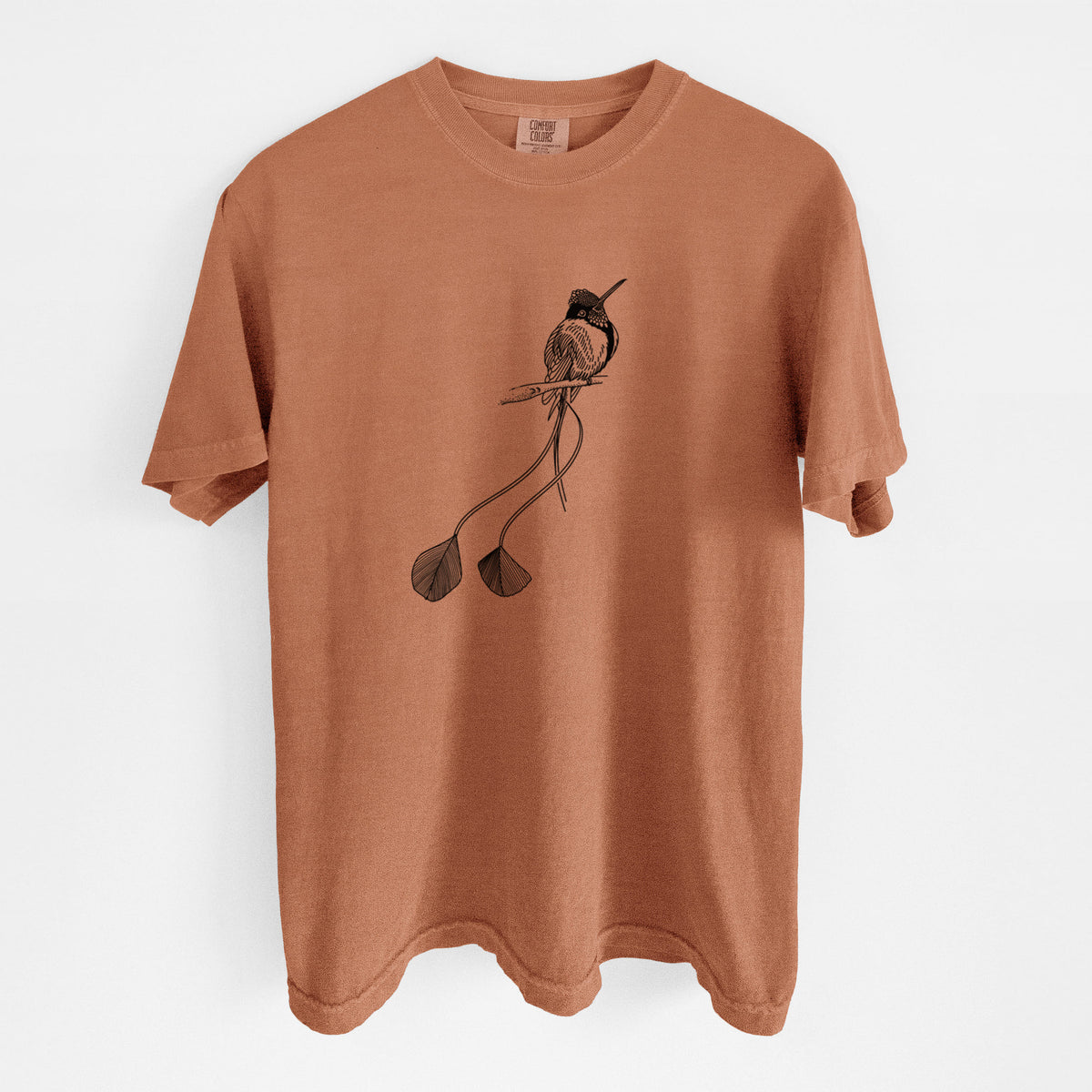 Yam burnt orange Comfort Colors t-shirt laid flat, printed with a black ink illustration of a marvelous spatuletail hummingbird perched, with its two long racket-tipped tail feathers.