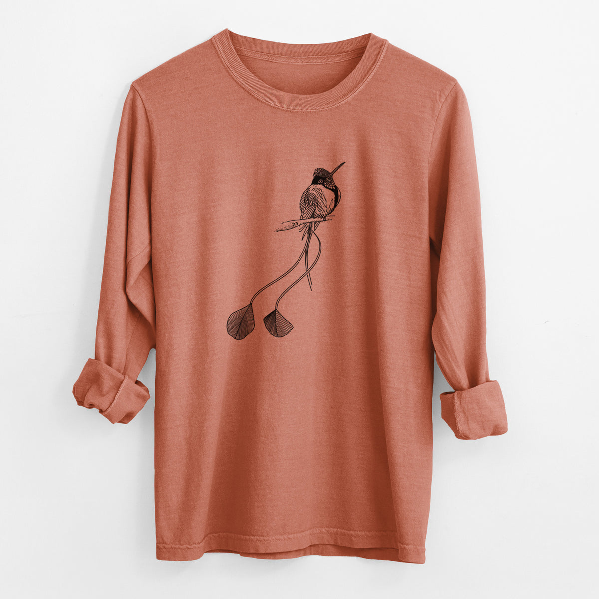 Yam burnt orange Comfort Colors long sleeve shirt laid flat with the cuffs rolled, printed with a black ink illustration of a marvelous spatuletail hummingbird perched, with its two long racket-tipped tail feathers.