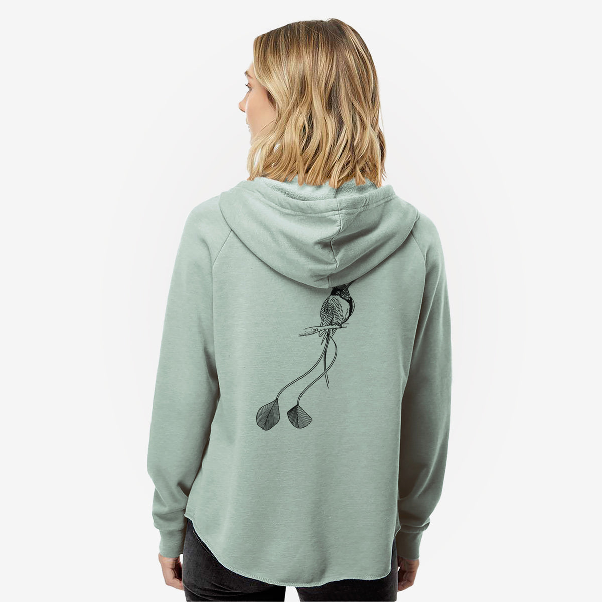 Woman wearing a sage green women's Cali Wave zip-up sweatshirt printed with a black ink illustration of a marvelous spatuletail hummingbird perched, with its two long racket-tipped tail feathers, seen from behind.