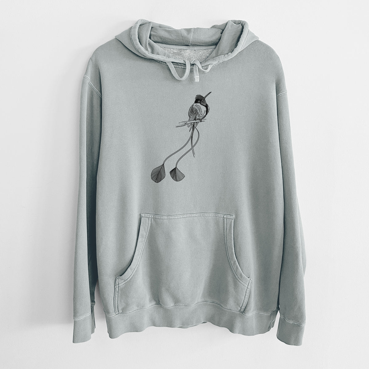 Sage green pigment dyed hoodie laid flat, printed with a black ink illustration of a marvelous spatuletail hummingbird perched, with its two long racket-tipped tail feathers.