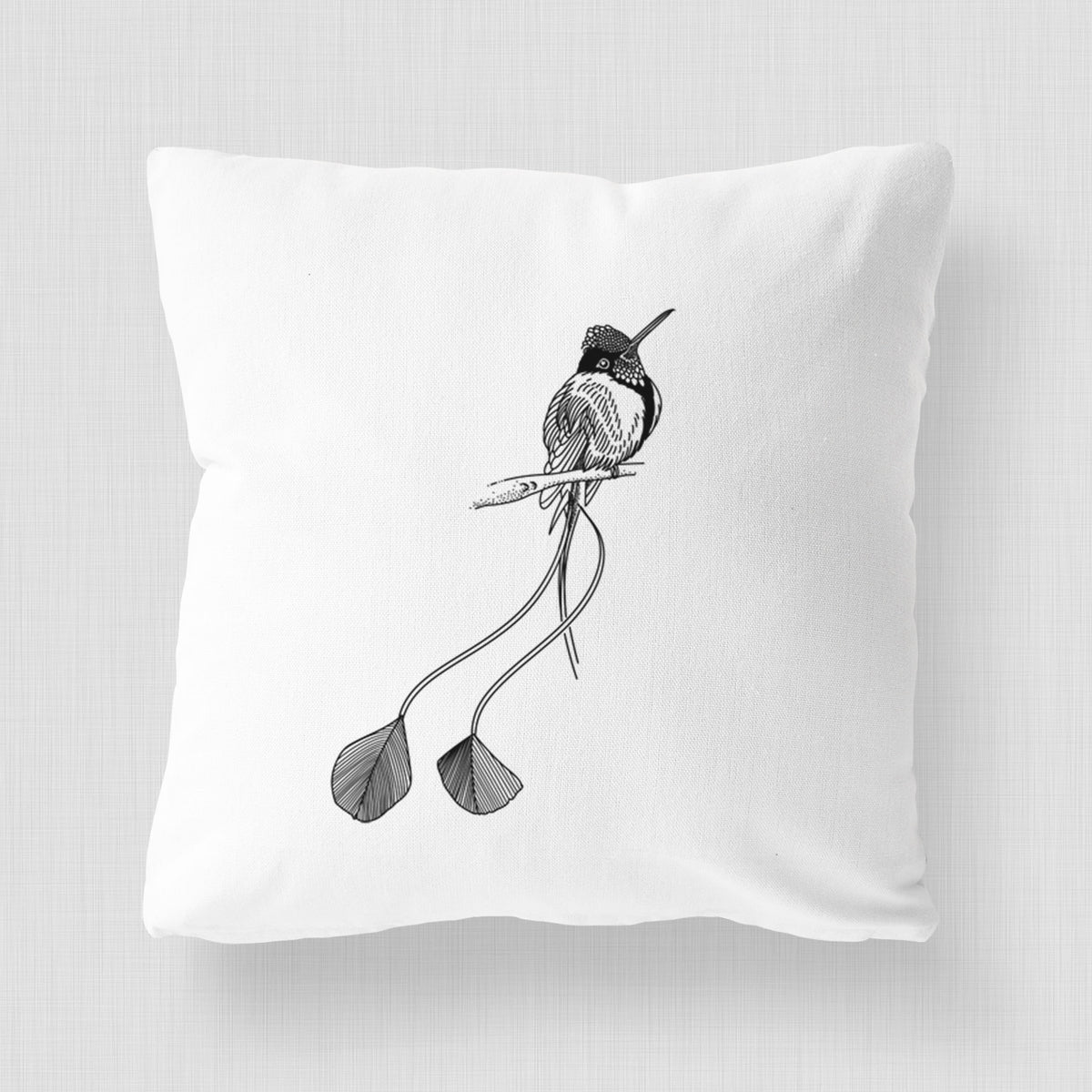 White pillow cover printed with a black ink illustration of a marvelous spatuletail hummingbird perched, with its two long racket-tipped tail feathers.