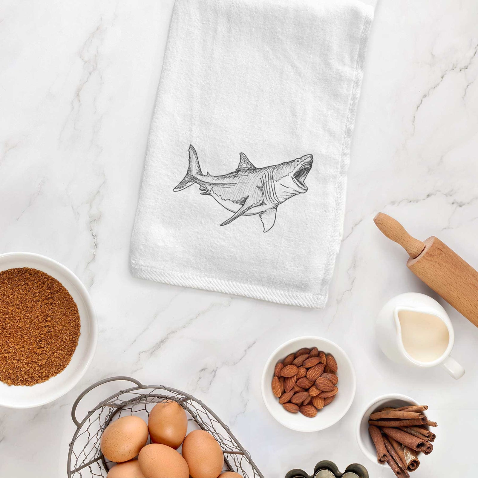 White hand towel printed with a black ink illustration of a megalodon shark with its jaws open.