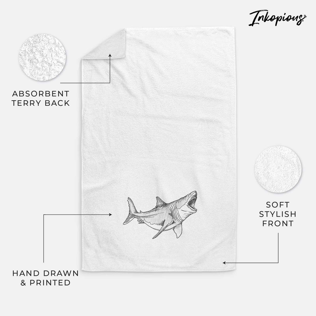 White hand towel printed with a black ink illustration of a megalodon shark with its jaws open.