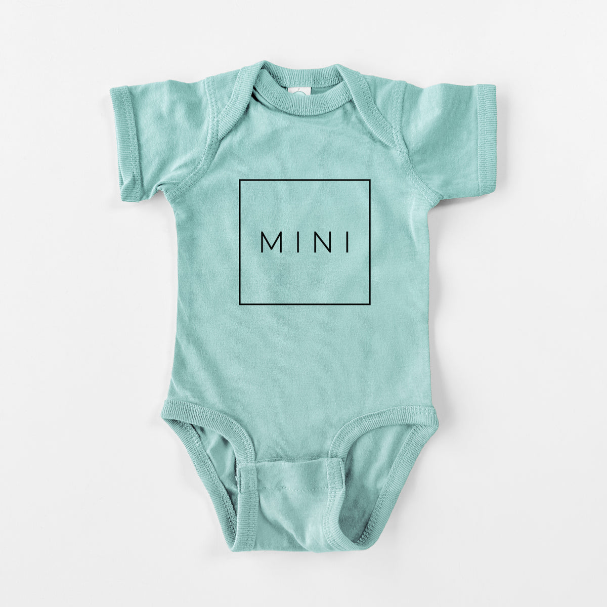 Saltwater baby bodysuit laid flat, printed with the word MINI in thin black letters inside a square outline.