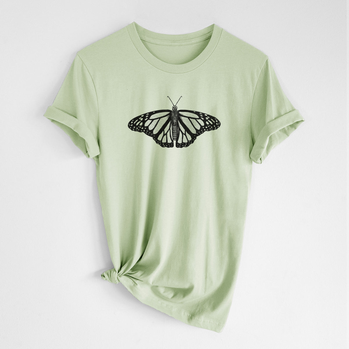 Spring green lightweight cotton t-shirt laid flat with the sleeves rolled, printed with a detailed black ink illustration of a monarch butterfly with its wings spread.