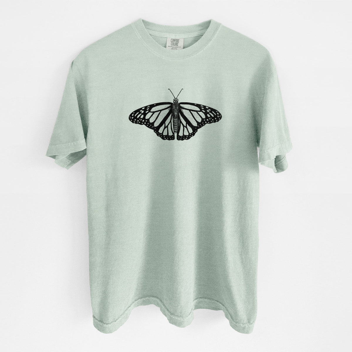 Bay green Comfort Colors t-shirt laid flat, printed with a detailed black ink illustration of a monarch butterfly with its wings spread.