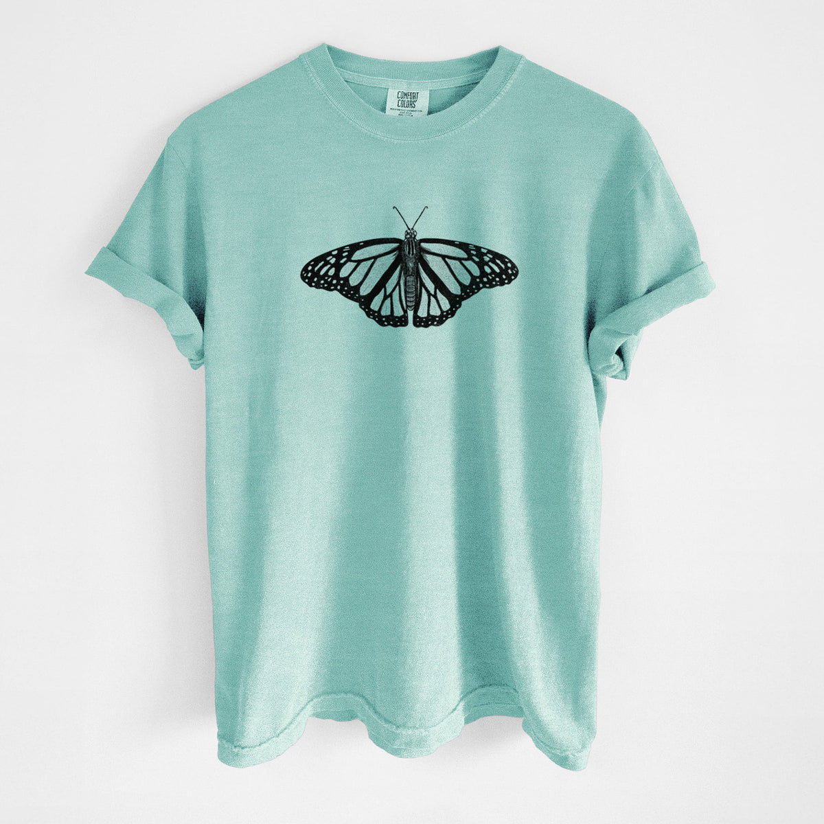 Chalky mint Comfort Colors t-shirt laid flat, printed with a detailed black ink illustration of a monarch butterfly with its wings spread.