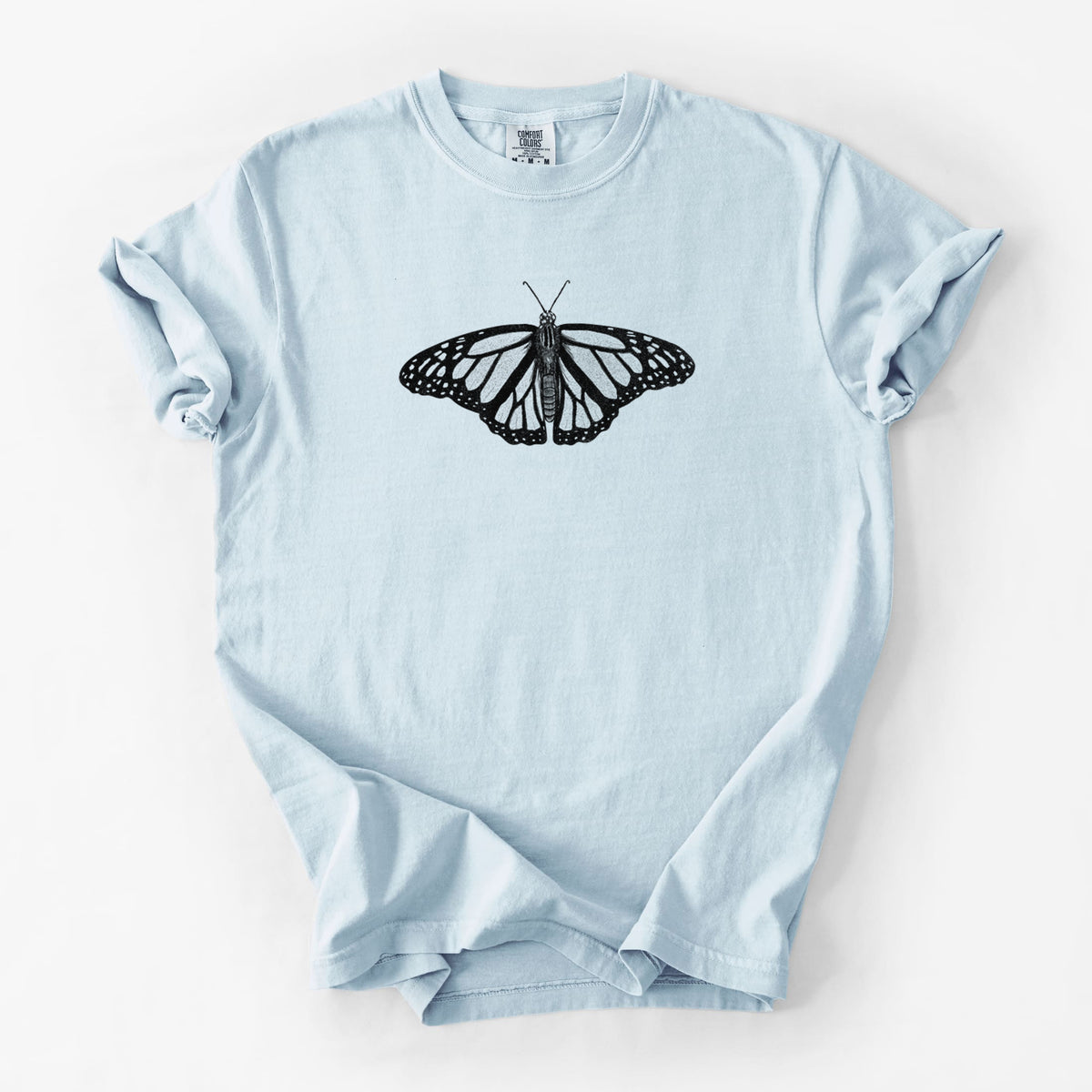 Chambray blue Comfort Colors t-shirt laid flat, printed with a detailed black ink illustration of a monarch butterfly with its wings spread.