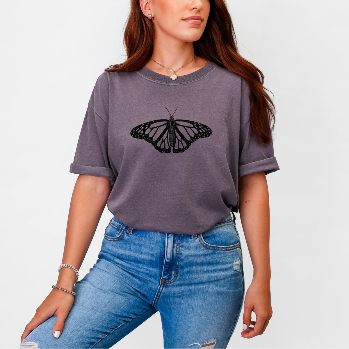 Woman wearing a Comfort Colors t-shirt printed with a detailed black ink illustration of a monarch butterfly with its wings spread.