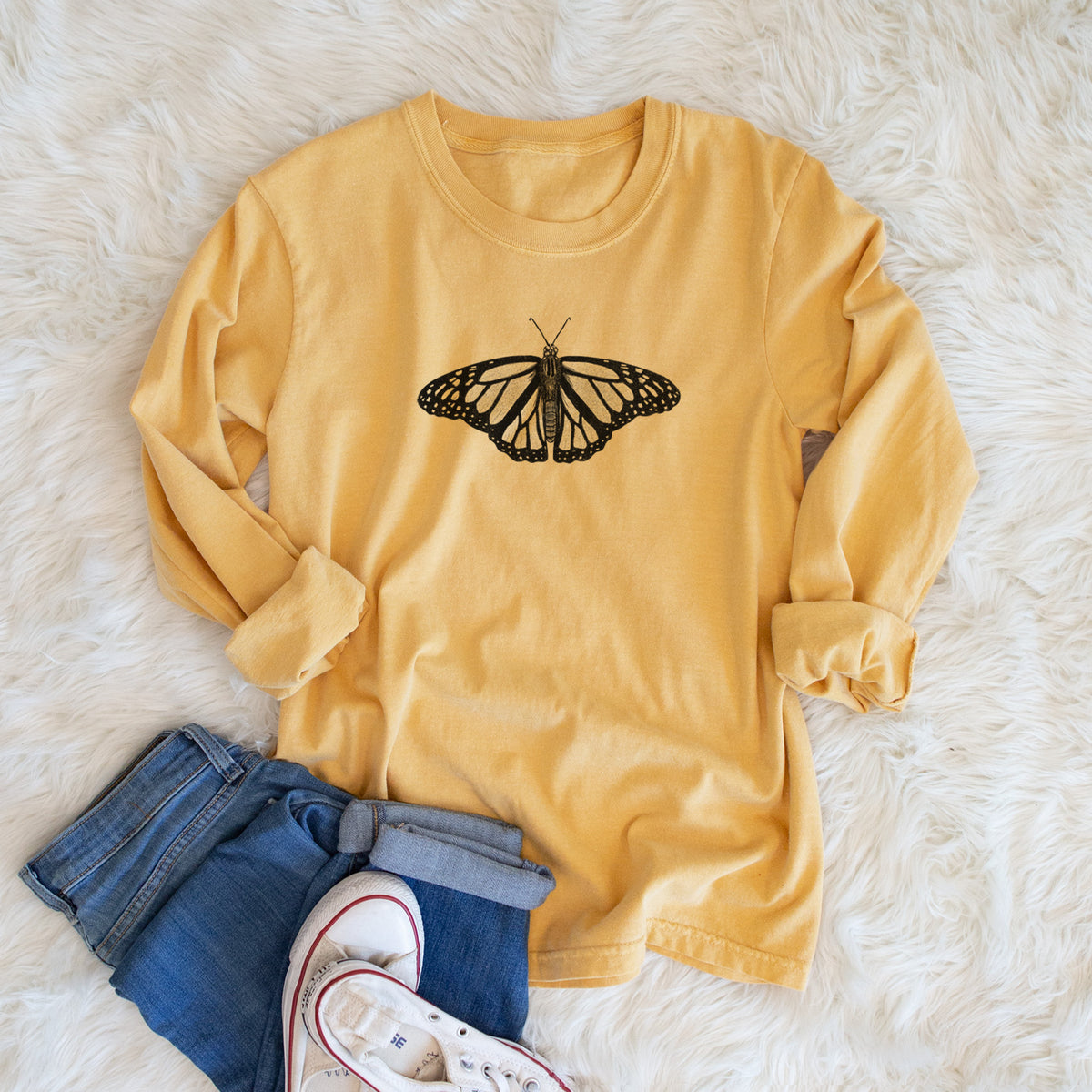 Golden wheat yellow Comfort Colors long sleeve shirt printed with a detailed black ink illustration of a monarch butterfly with its wings spread, shown in a lifestyle photo.