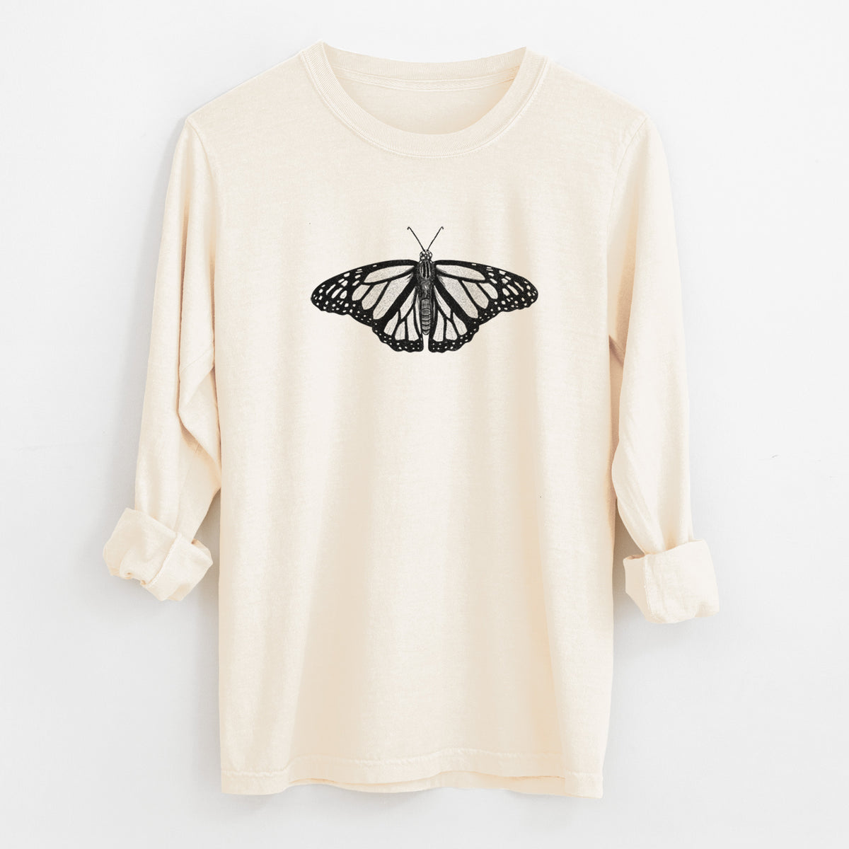Ivory Comfort Colors long sleeve shirt laid flat with the cuffs rolled, printed with a detailed black ink illustration of a monarch butterfly with its wings spread.