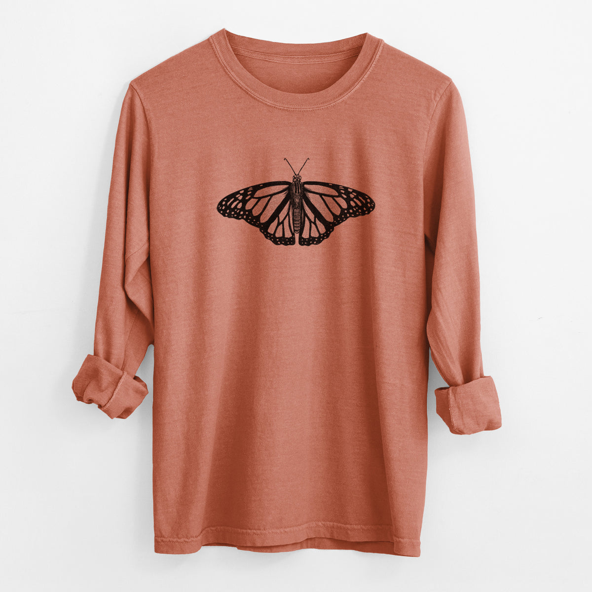 Yam burnt orange Comfort Colors long sleeve shirt laid flat with the cuffs rolled, printed with a detailed black ink illustration of a monarch butterfly with its wings spread.