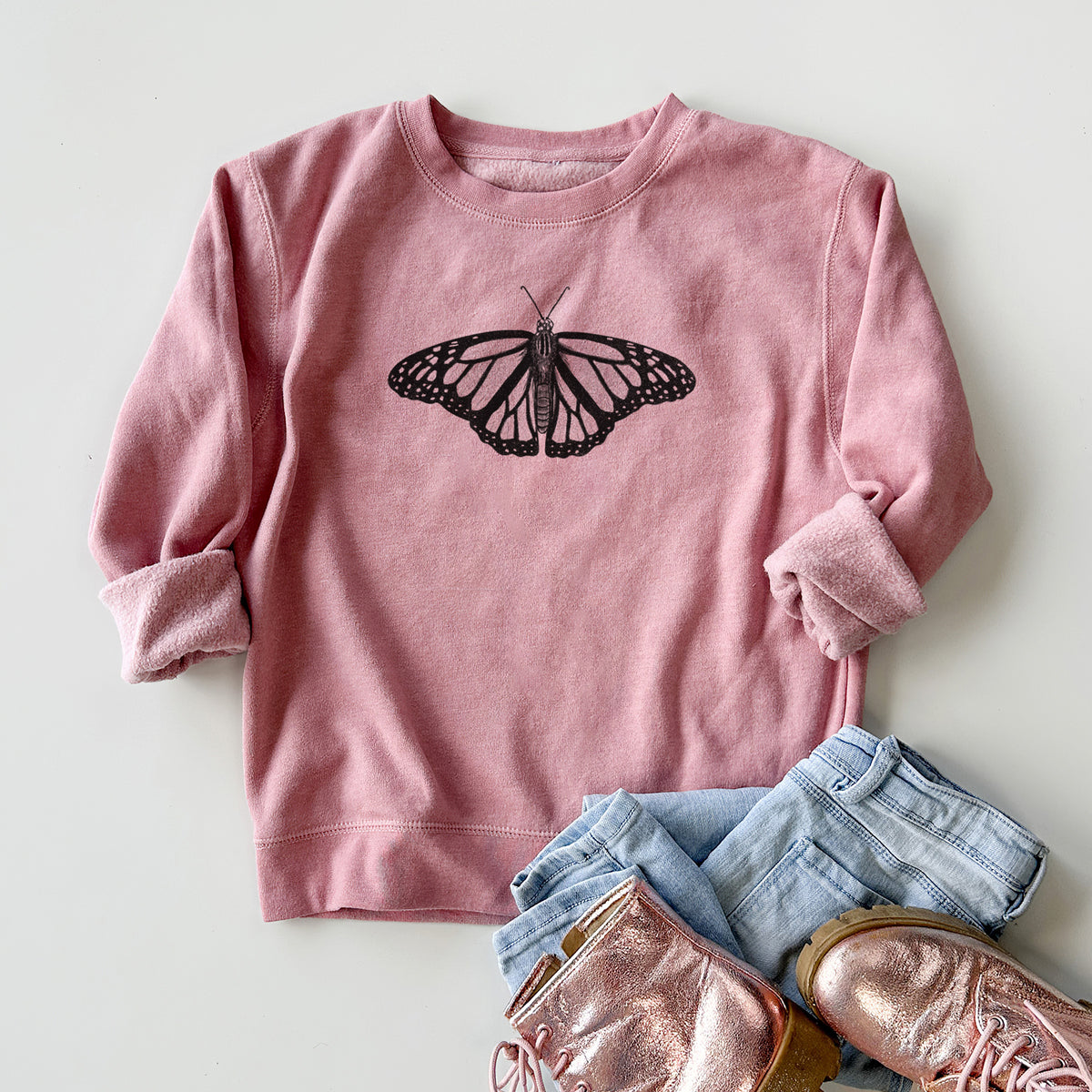 Youth crewneck sweatshirt printed with a detailed black ink illustration of a monarch butterfly with its wings spread, styled flat with jeans and boots.