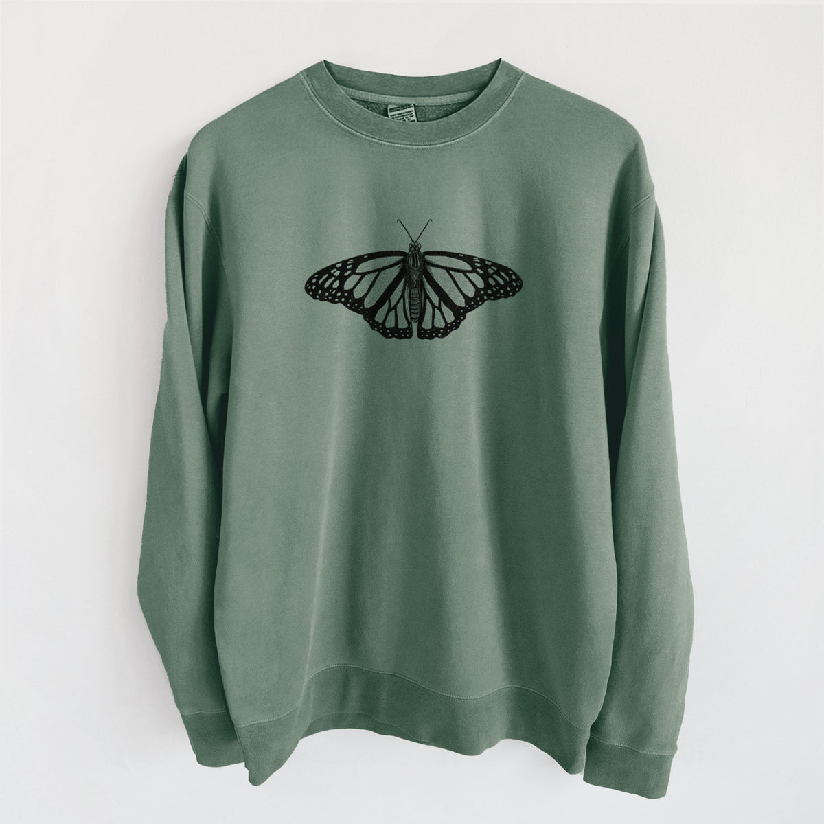 Alpine green pigment dyed crewneck sweatshirt laid flat, printed with a detailed black ink illustration of a monarch butterfly with its wings spread.
