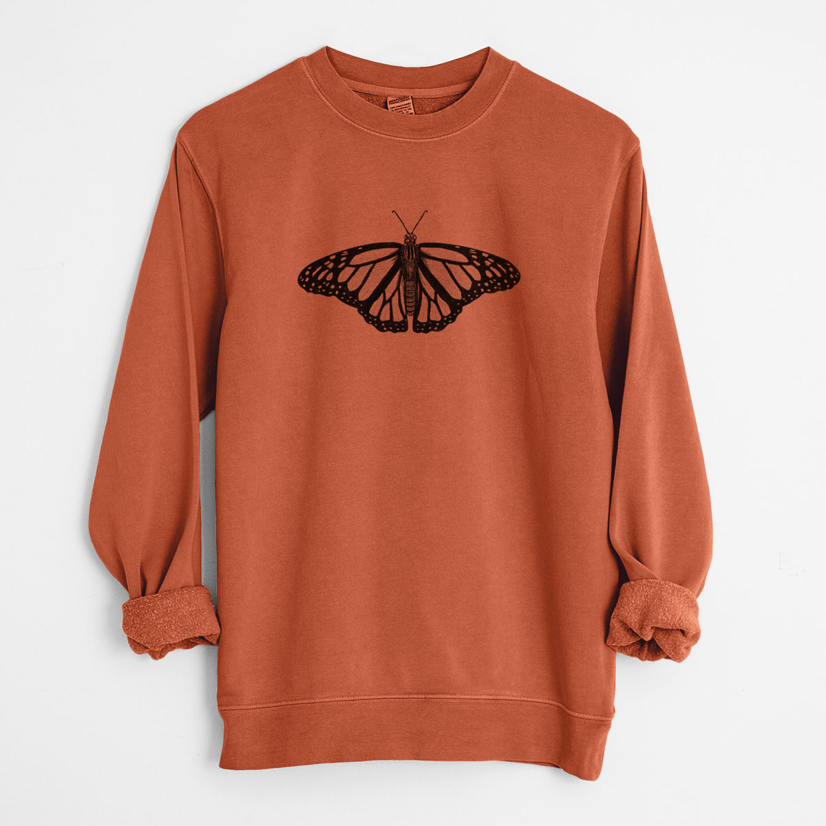 Amber orange pigment dyed crewneck sweatshirt laid flat with the sleeves rolled, printed with a detailed black ink illustration of a monarch butterfly with its wings spread.