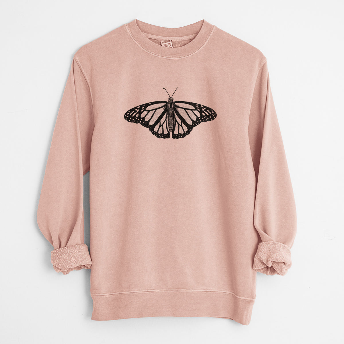 Dusty pink pigment dyed crewneck sweatshirt laid flat with the sleeves rolled, printed with a detailed black ink illustration of a monarch butterfly with its wings spread.