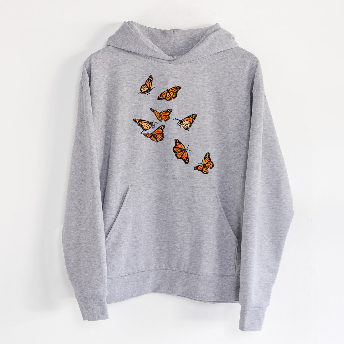 Monarch Migration - Statement Midweight Hoodie in Heather Grey, hanging on a white wall, with a front kangaroo pocket and no drawcords.
