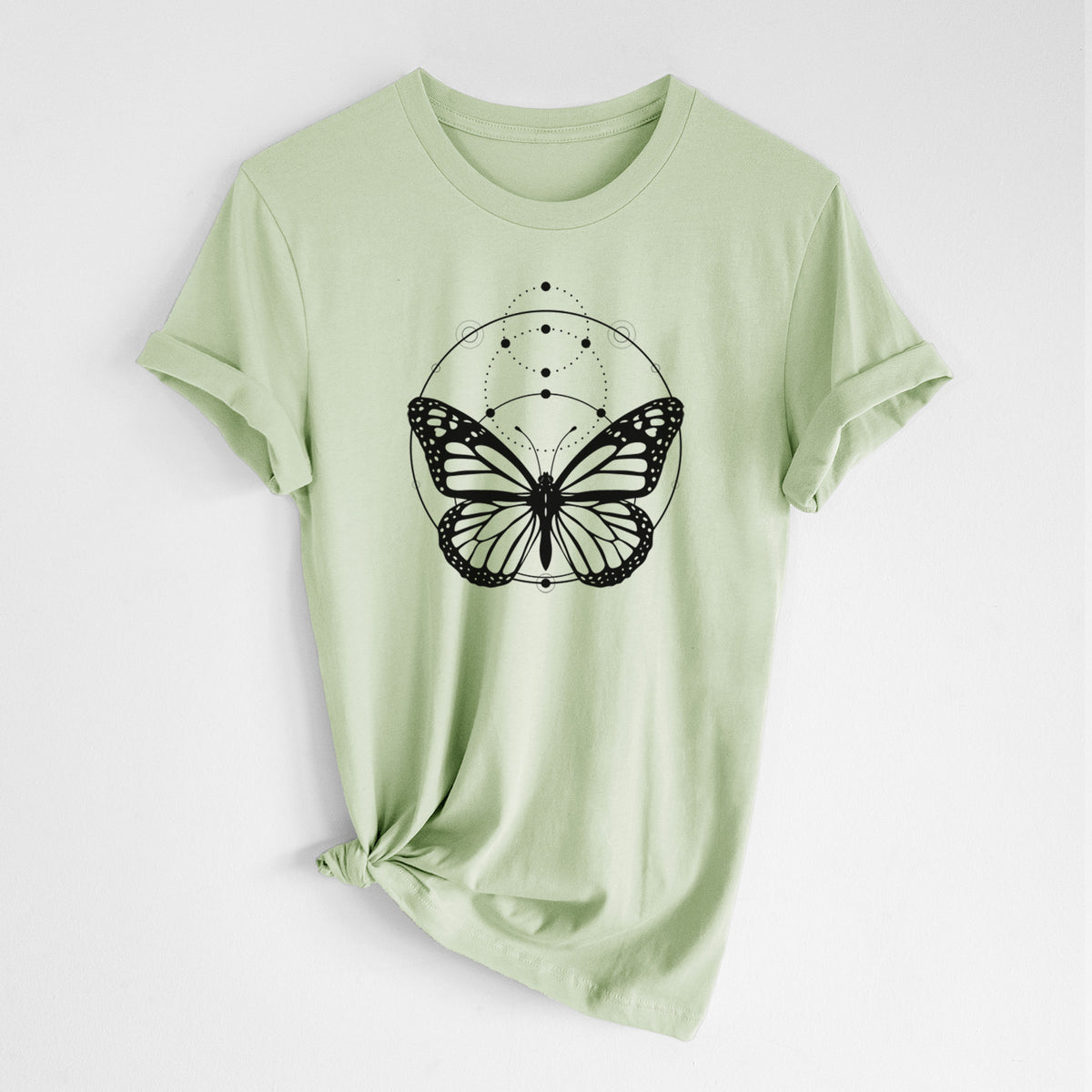 Spring green lightweight cotton t-shirt laid flat with the sleeves rolled, printed with a black ink monarch butterfly inside a circle, beneath a line of moon phases.