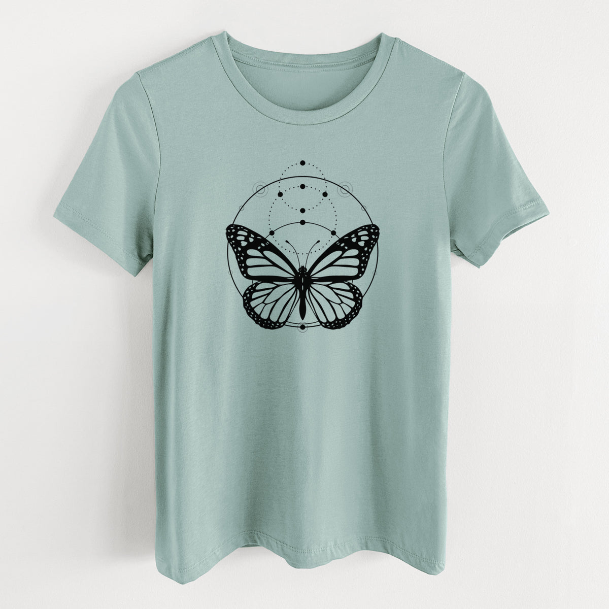 Dusty blue women's relaxed fit cotton t-shirt laid flat, printed with a black ink monarch butterfly inside a circle, beneath a line of moon phases.