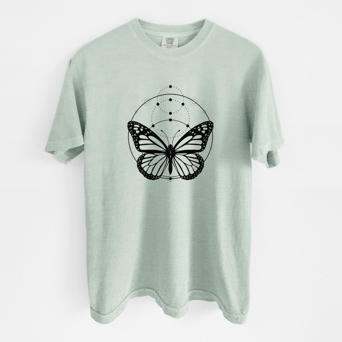 Bay green Comfort Colors t-shirt laid flat, printed with a black ink monarch butterfly inside a circle, beneath a line of moon phases.