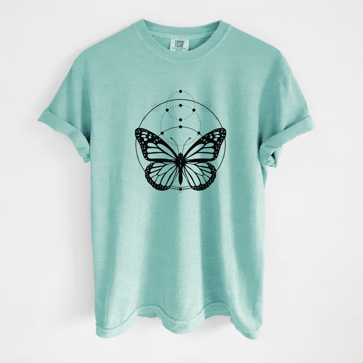 Chalky mint Comfort Colors t-shirt laid flat, printed with a black ink monarch butterfly inside a circle, beneath a line of moon phases.