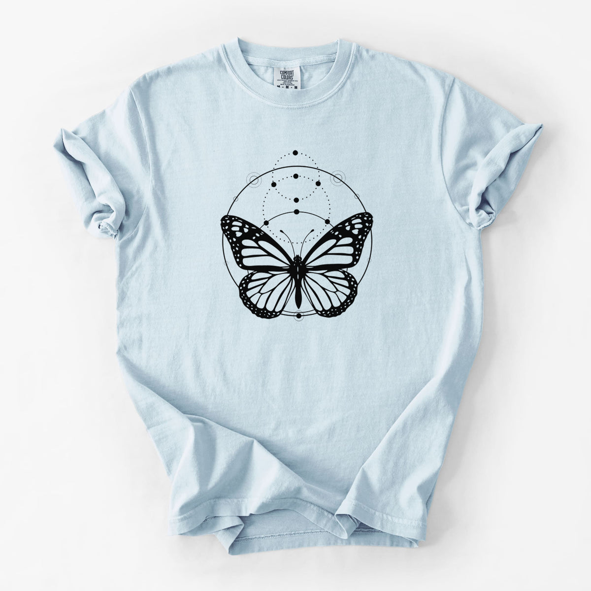 Chambray blue Comfort Colors t-shirt laid flat, printed with a black ink monarch butterfly inside a circle, beneath a line of moon phases.