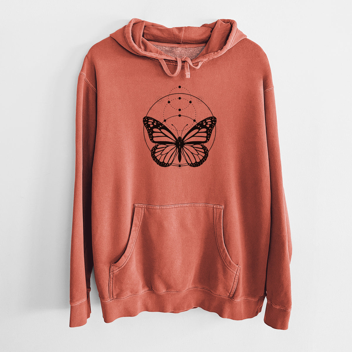 Amber orange pigment dyed hoodie laid flat, printed with a black ink monarch butterfly inside a circle, beneath a line of moon phases.