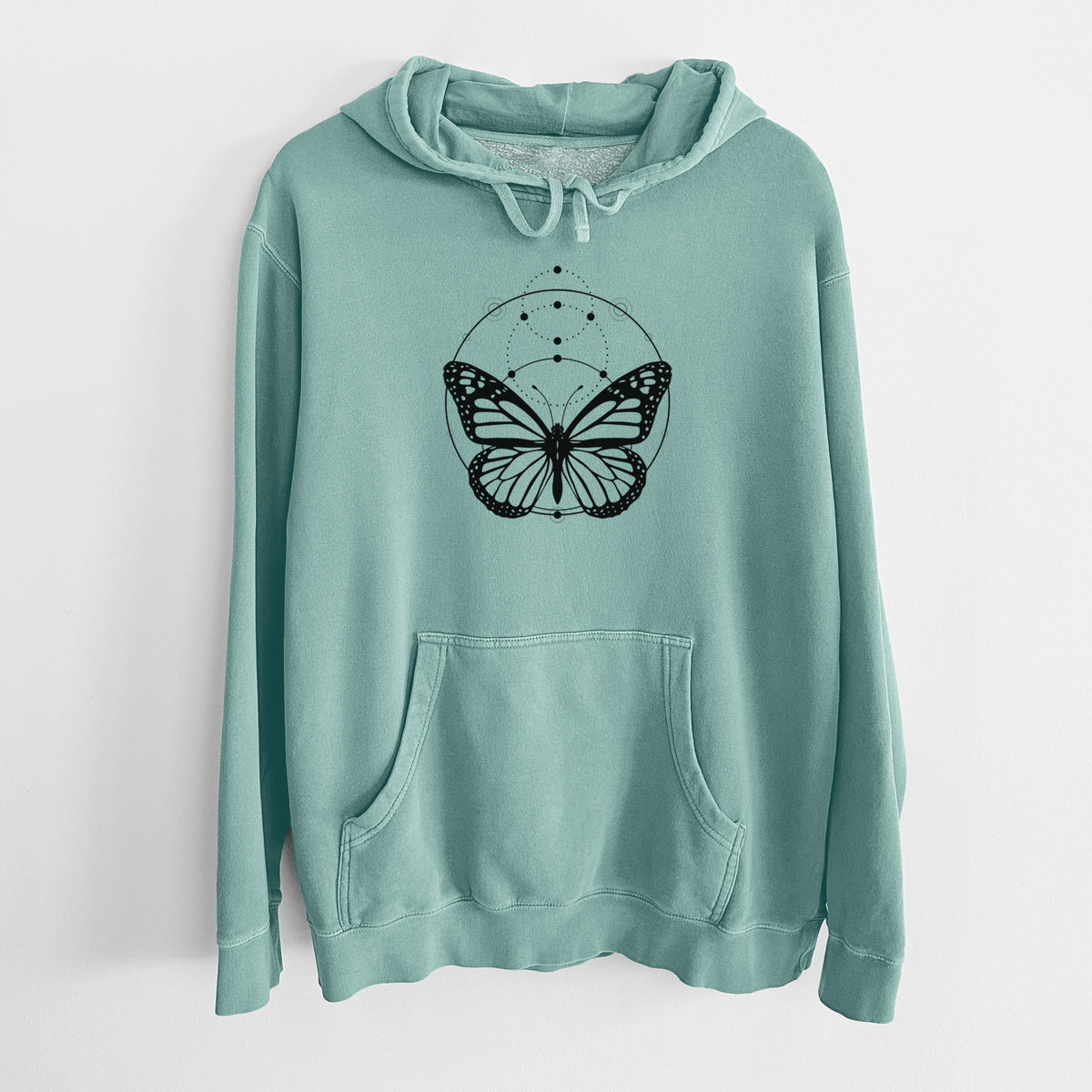 Mint green pigment dyed hoodie laid flat, printed with a black ink monarch butterfly inside a circle, beneath a line of moon phases.