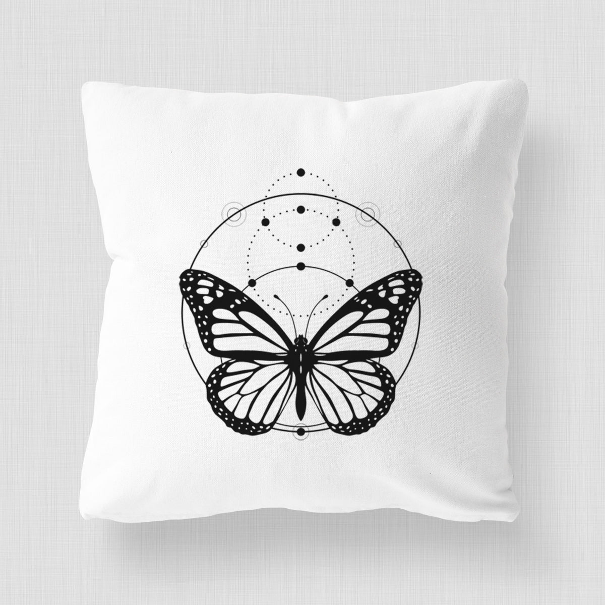 White pillow cover printed with a black ink monarch butterfly inside a circle, beneath a line of moon phases.