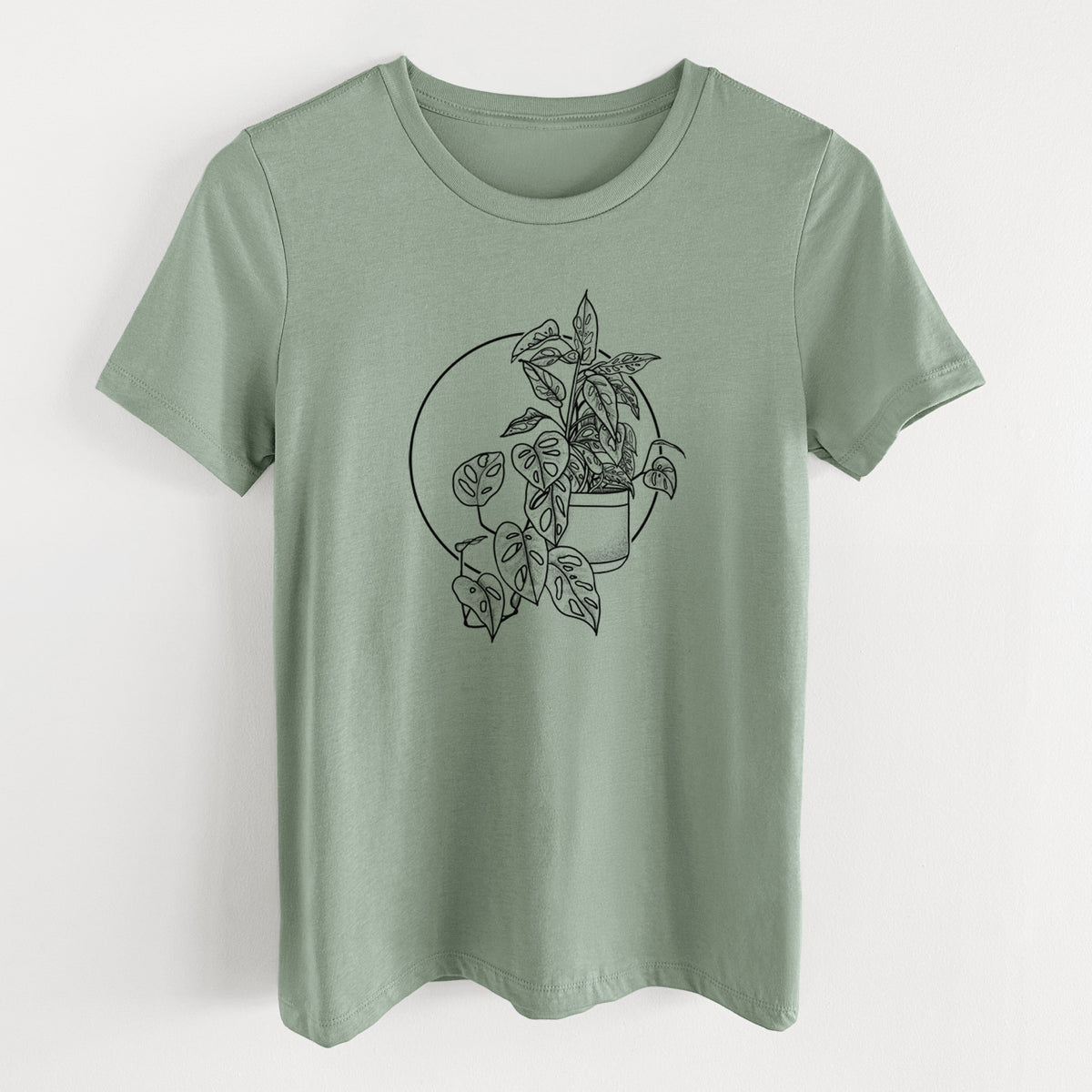 Sage green women's relaxed fit cotton t-shirt laid flat, printed with a black ink illustration of a potted Monsteradansonii plant with trailing vines in front of a circle.