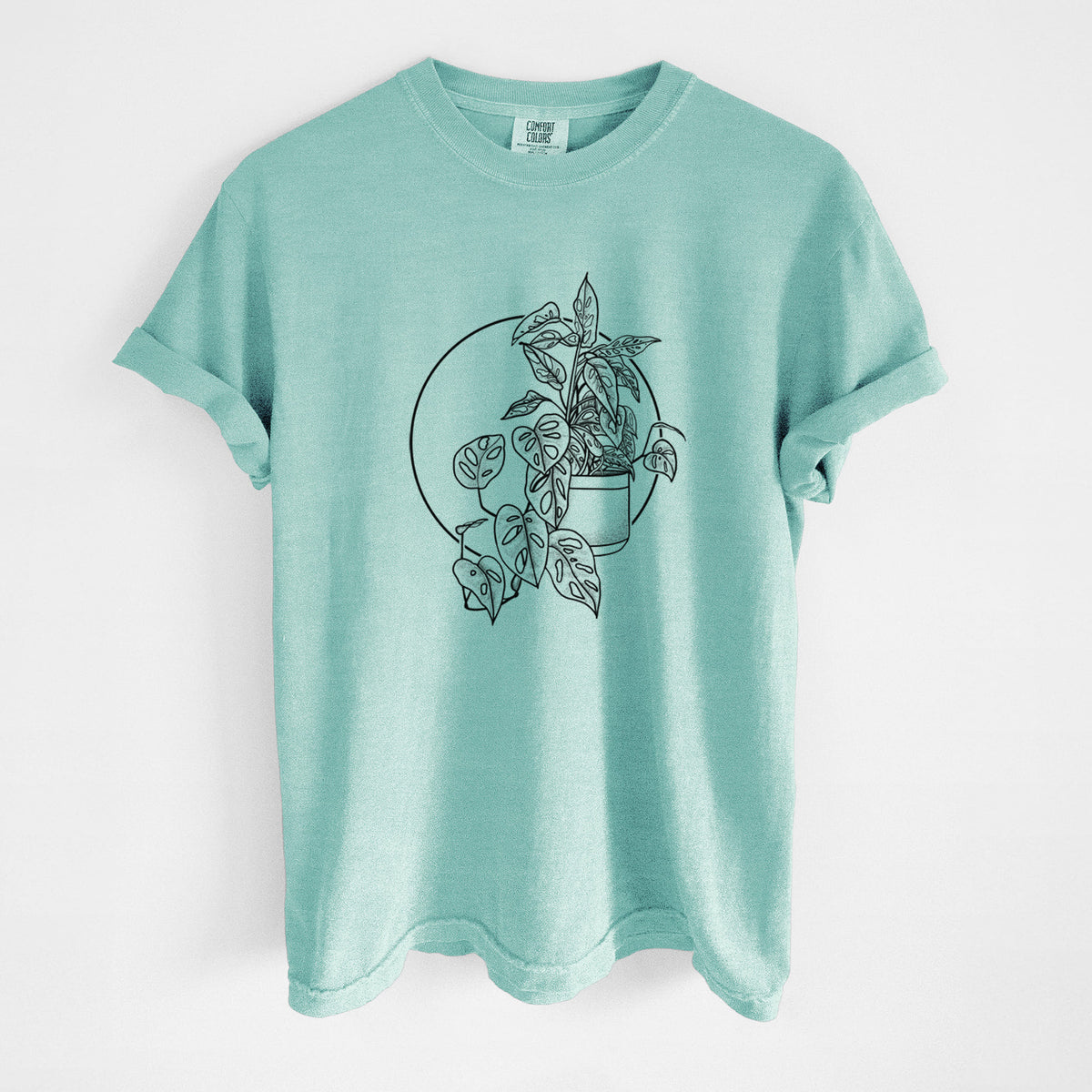 Chalky mint Comfort Colors t-shirt laid flat, printed with a black ink illustration of a potted Monsteradansonii plant with trailing vines in front of a circle.