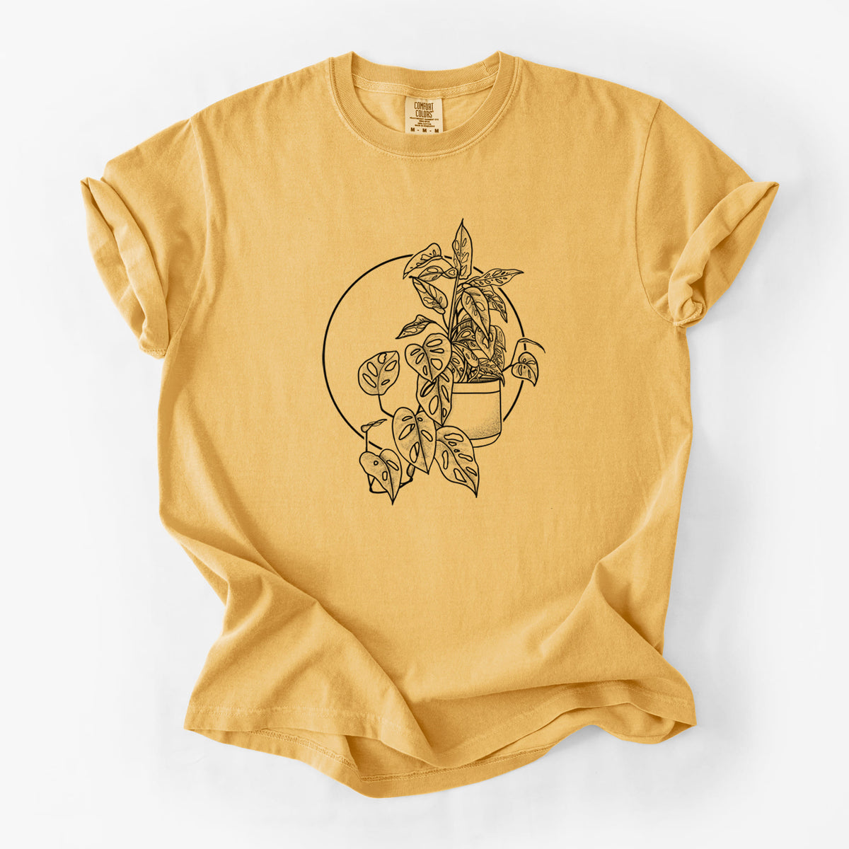 Golden wheat yellow Comfort Colors t-shirt laid flat, printed with a black ink illustration of a potted Monsteradansonii plant with trailing vines in front of a circle.