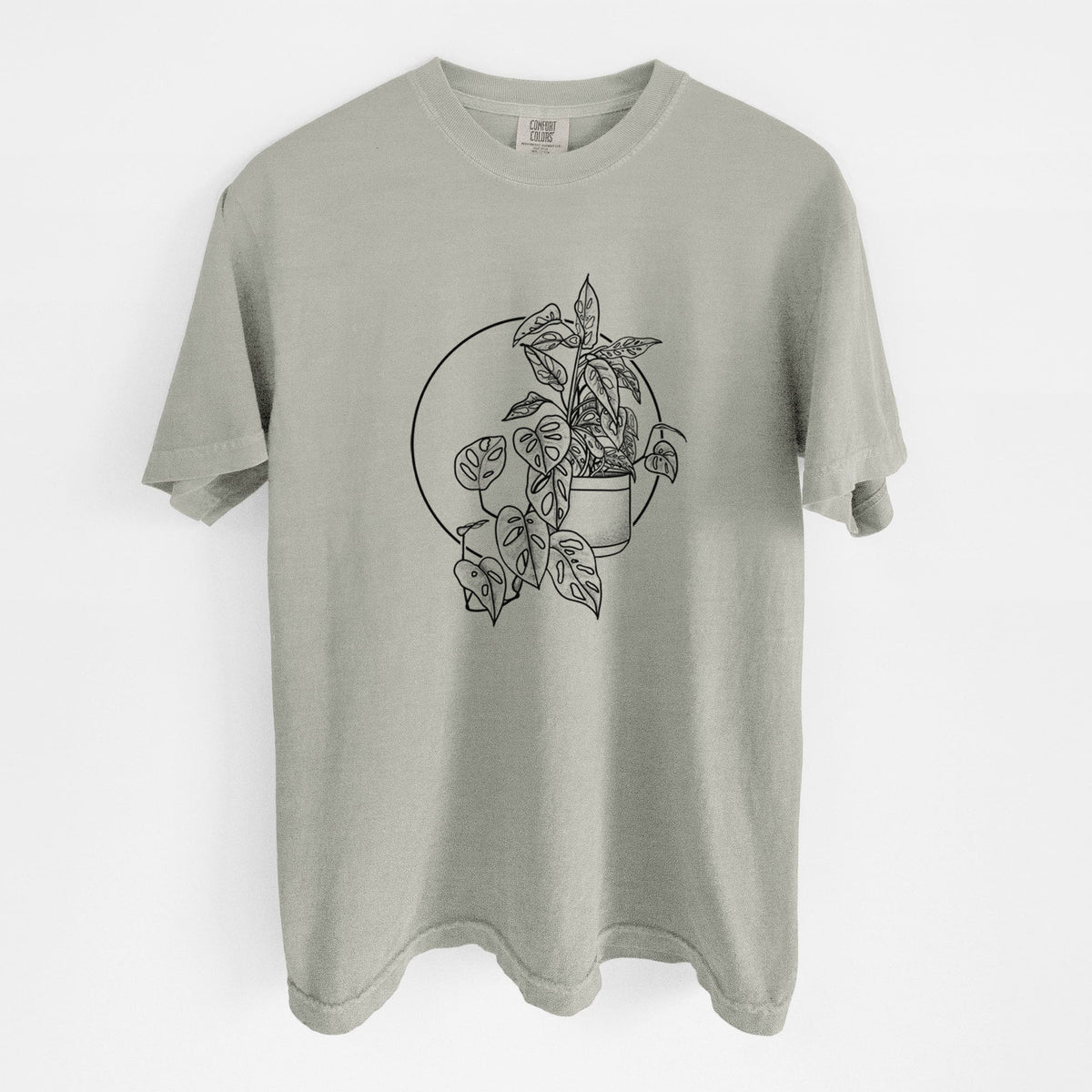 Sandstone beige Comfort Colors t-shirt laid flat, printed with a black ink illustration of a potted Monsteradansonii plant with trailing vines in front of a circle.