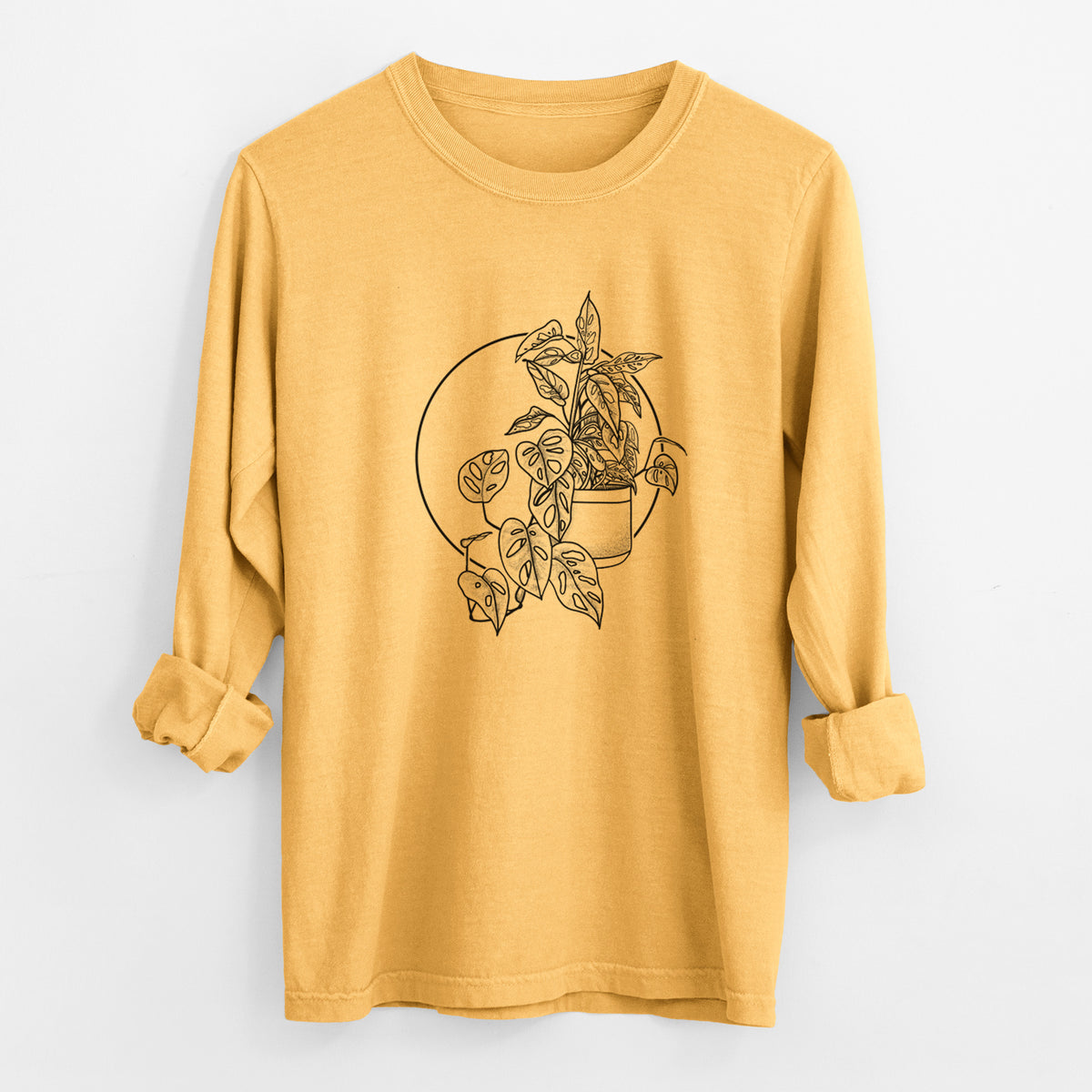 Golden wheat yellow Comfort Colors long sleeve shirt laid flat with the cuffs rolled, printed with a black ink illustration of a potted Monsteradansonii plant with trailing vines in front of a circle.
